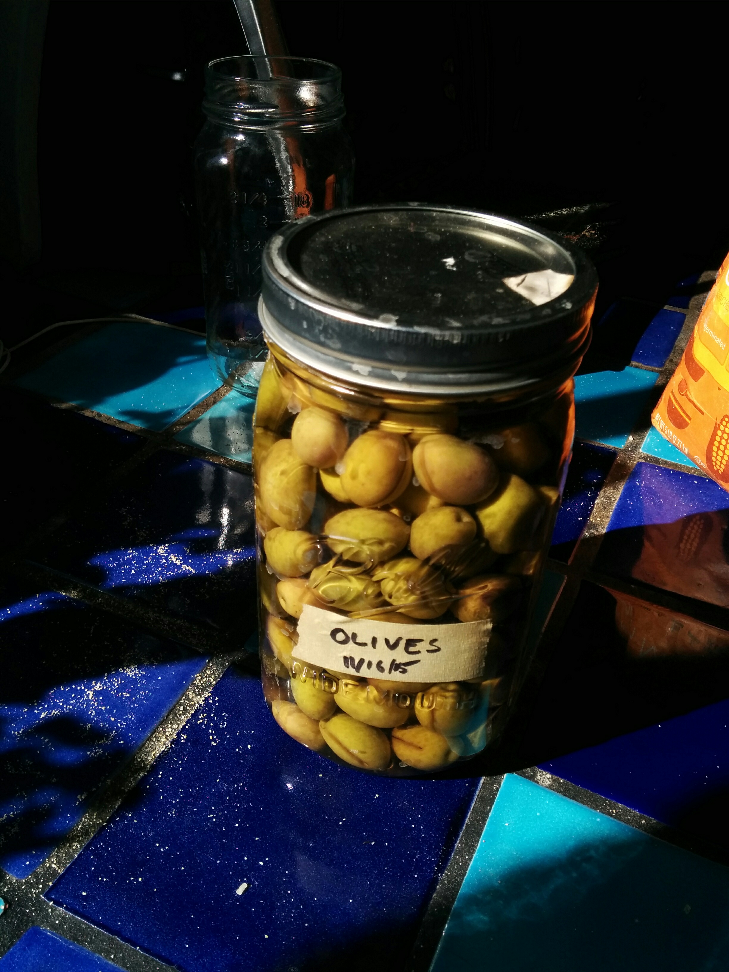 One of four jars of olives brine-curing.
